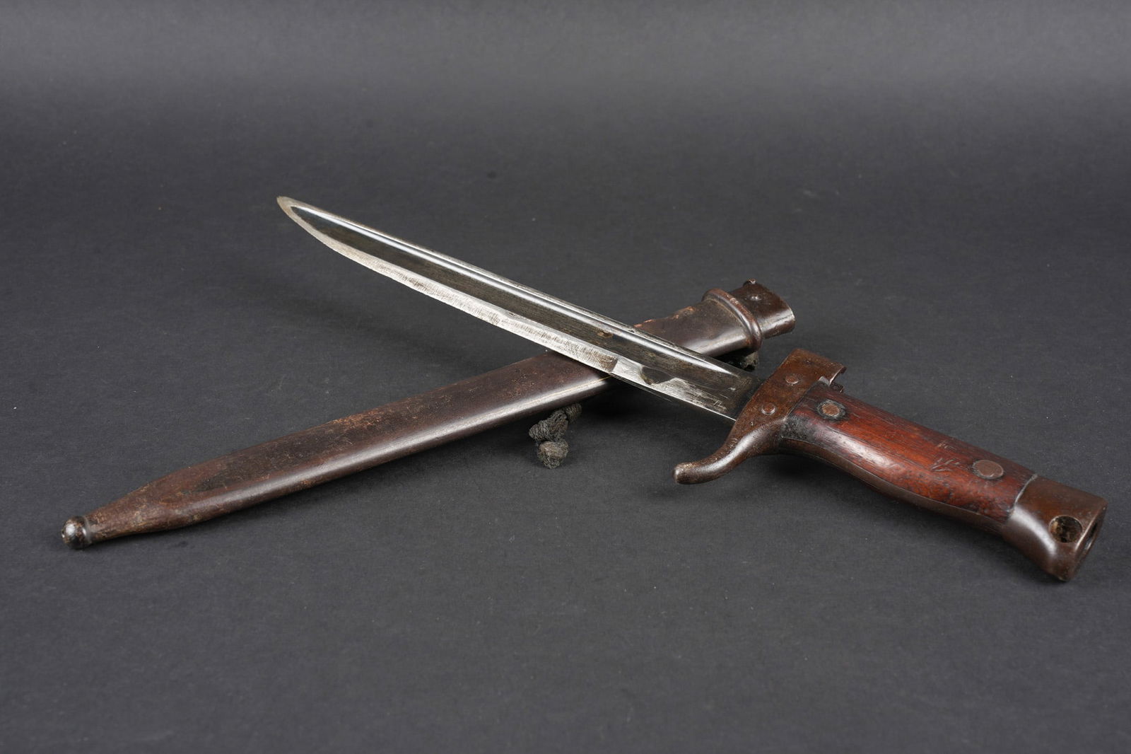 Baionnette Berthier raccourcie. Shortened Berthier bayonet: Baionnette Berthier raccourcie. Quillon raccourci, plaquettes en bois, bouton poussoir supprime, fourreau raccourci presentant quelques bosses et pas au meme numero. Lame possedant encore une partie d