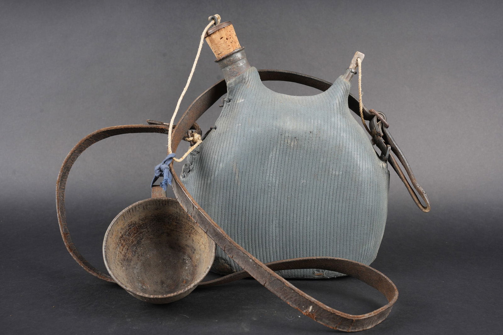 Bidon 1877 ersatz. Improvised (ersatz) Model 1877 water bottle: Bidon 1877 ersatz. Bidon modele 1877 de deux litres, fabrique en fer etame. Housse en drap velours peinte en bleu horizon. Etiquette en coton attribuant l effet au soldat Robert, courroie en cuir rive