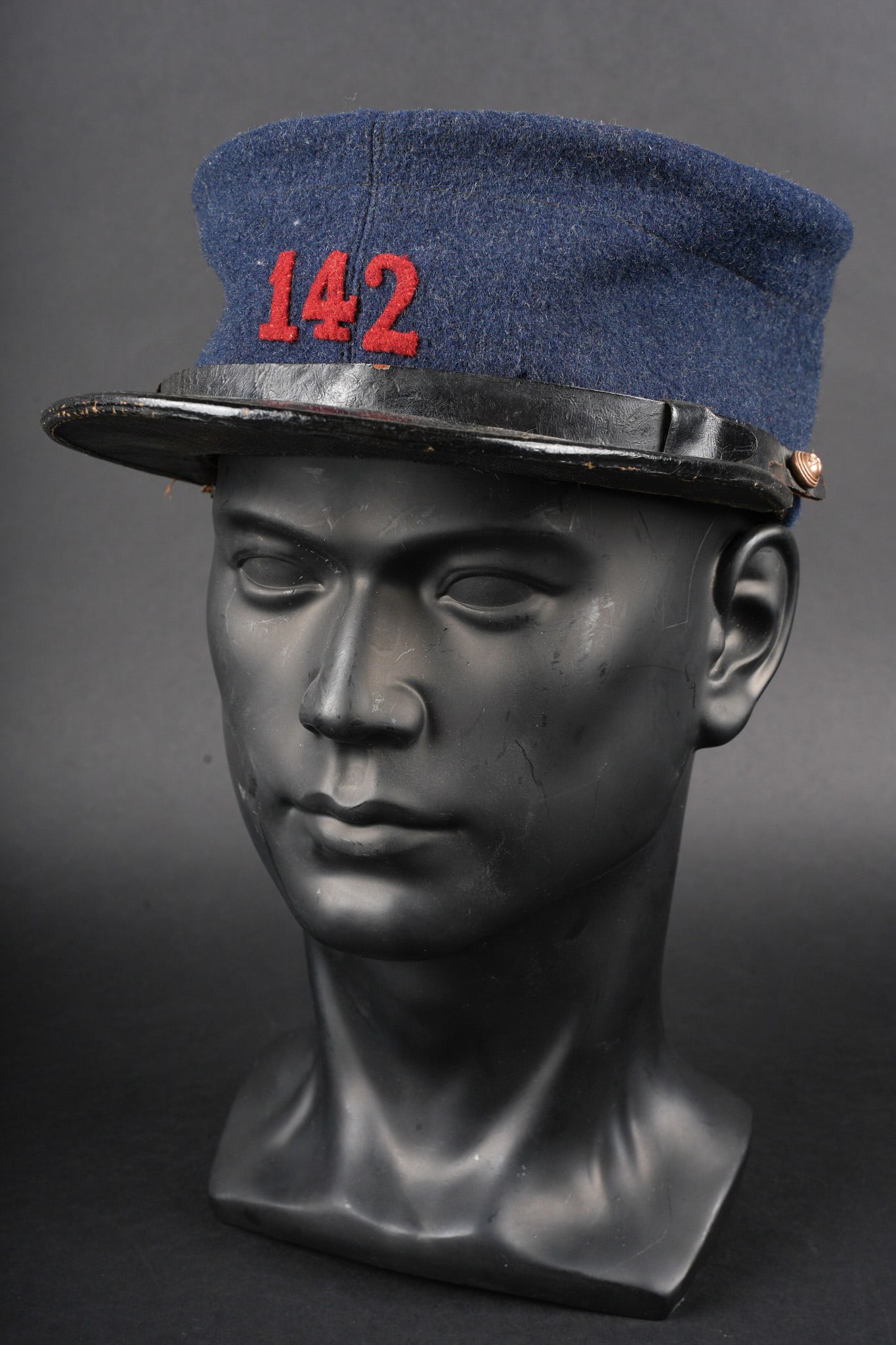 Kepi sous officier 142eme RI. Kepi, NCO, 142nd Infantry Regiment: Kepi sous officier 142eme RI. En drap gris de fer bleute, chiffres rapportees en drap garance, fausse jugulaire en cuir noir retenue par deux petits boutons aux armes de l infanterie. Visiere en cuir