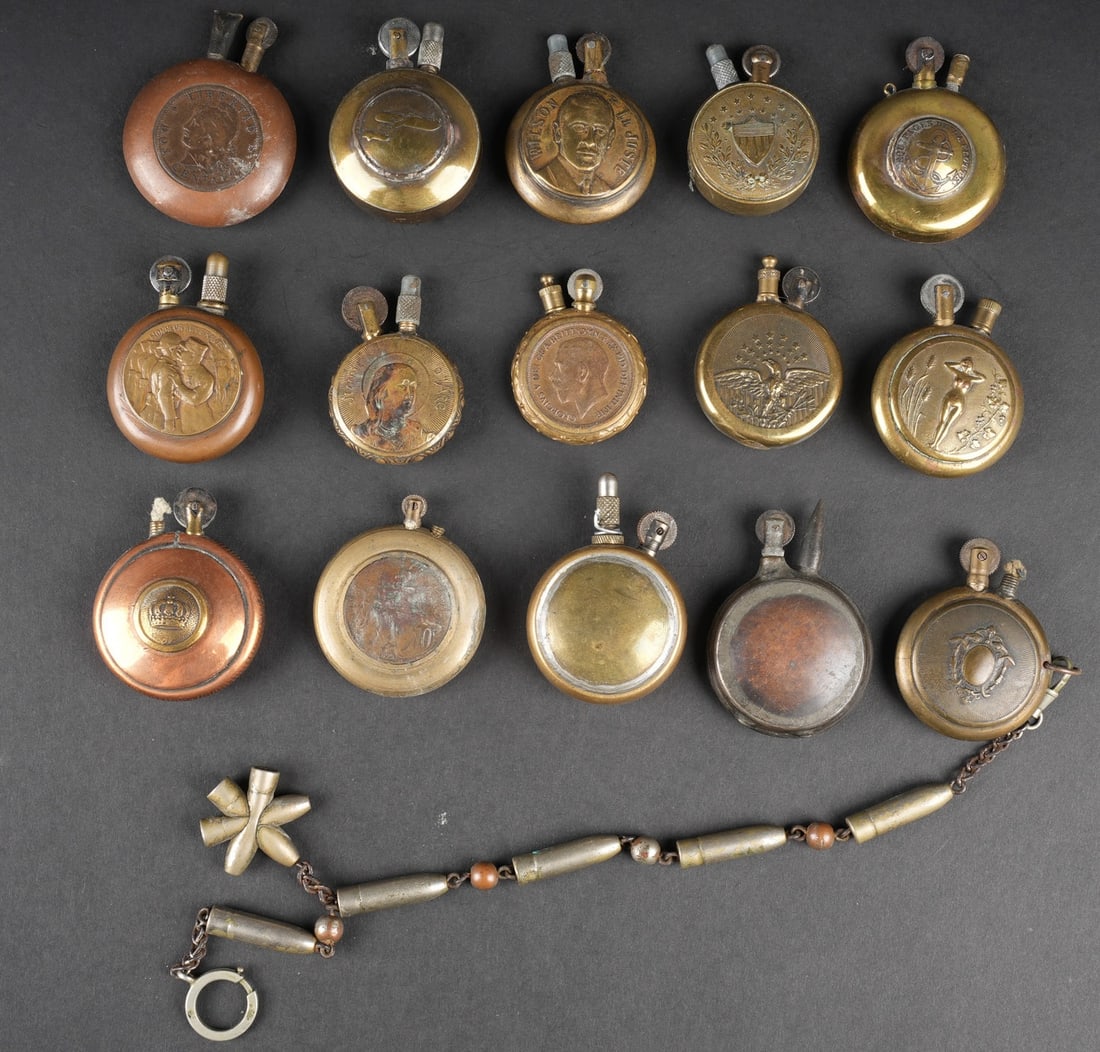 Lot artisanat de tranchees briquets. Lot of trench-art lighters: Lot artisanat de tranchees briquets. Comprenant quinze briquets en laiton et cuivre. Quatre modeles americain, un modele portant un bouton des equipages de la flotte, un avec un avion, un avec un bout