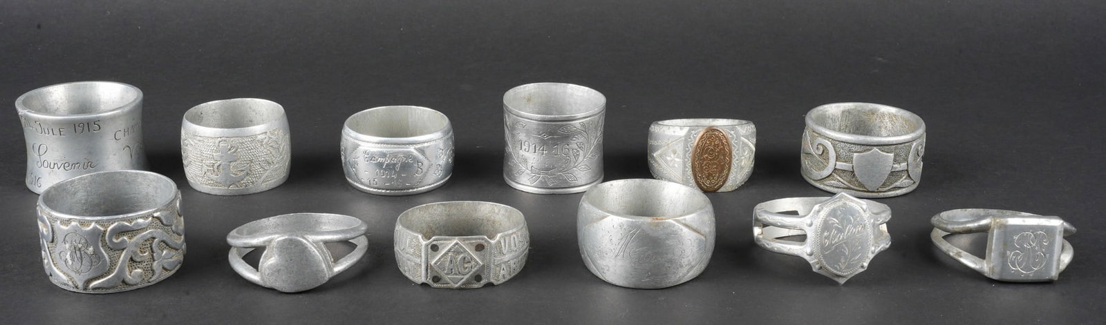 Lot artisanat de tranchees. Lot of trench art: Lot artisanat de tranchees. Comprenant douze ronds de serviette, un au decor de fleurs portant la mention 14, 15, 16, un en forme de bague avec un motif central en laiton grave d initiales, un en