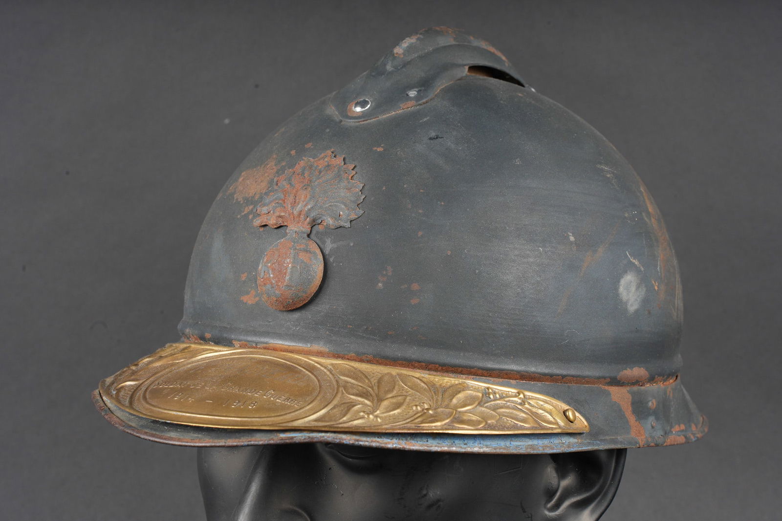 Casque Adrian 1915 nominatif. Named Adrian helmet, Model 1915: Casque Adrian 1915 nominatif. Coque de casque modele 1915, peinture bleu fonce d usine. Attribut frontal modele 1915 de l infanterie. Au fond de la coiffe on trouve le marquage fabricant Le jouet de P