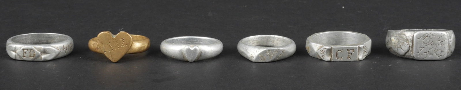 Ensemble de 6 bagues artisanat de tranchee. Set of six trench art rings: Ensemble de 6 bagues artisanat de tranchee. 5 en aluminium, 1 en laiton, certaines avec initiales ou nom, 4 d entre elles comportent des dates 1914 et/ou 1915. Usure d usage. Set of six trench art rin