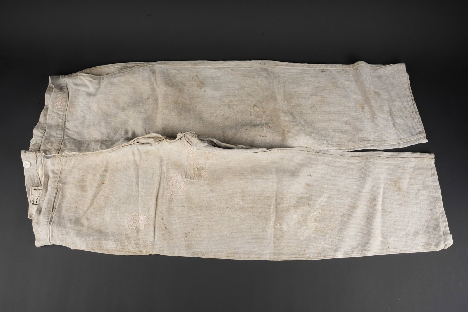 Pantalon Bourgeron 75ieme BAF. Bourgeron trousers 75th BAF: Pantalon Bourgeron 75ieme BAF. Pantalon bourgeron confectionne en lin ecru. Sur la doublure de la poche a gousset se trouve a deux reprises du 75ieme Bataillon d Artillerie de Forteresse. Martingale c