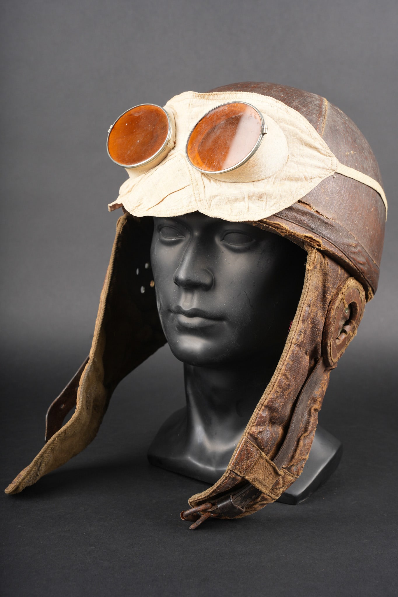 Casque de vol simplifie. Simplified flight helmet: Casque de vol simplifie. Casque de type Roold de fabrication simplifiee, bombe en liege recouverte d un cuir fin marron, proteges oreilles possedant quatre œillets chacun. Bas volets doubles en fine