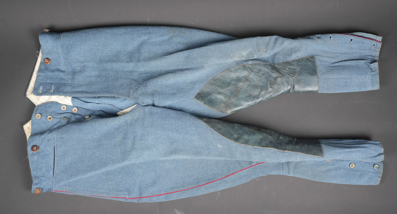Culotte artillerie montee. Mounted artillery breeches: Culotte artillerie montee. Realisee en drap bleu horizon type officier, passepoil rouge de l artillerie. Culotte se fermant par sept boutons, renfort de cuir a l entrejambe, manchettes se fermant par