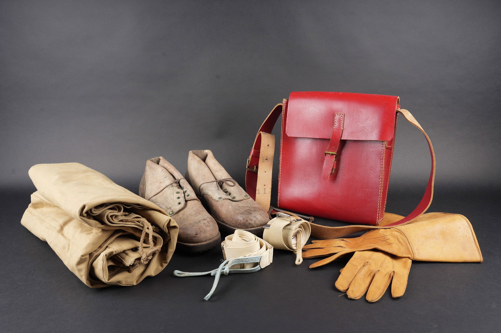 Ensemble d equipements. Set of equipment: Ensemble d equipements. Comprenant une paire de brodequins modele 1945 neuf de stock. Une sacoche d officier spahis en cuir gaufre rouge, complete avec sa sangle et son systeme de fixation, tampon du