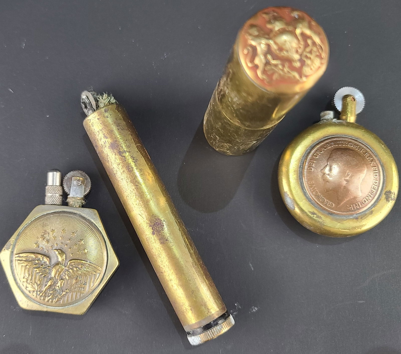 Briquets de tranchees anglais et americain.: Briquets de tranchees anglais et americain. Un briquet rond avec de part et d autre une piece de 1 penny, l une de epoque Victoria, l autre Georges V. Un briquet laiton cylindrique avec sur le dessus