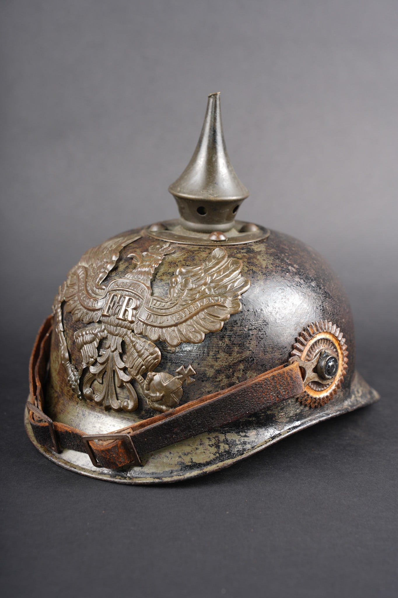 Casque a pointe prussien ersatz en tole feldgrau retrouve en Haute-Saone. Prussian ersatz: Casque a pointe prussien ersatz en tole feldgrau retrouve en Haute-Saone. Casque en tole d acier, peinte feldgrau avec encore 25 a 30 % de sa peinture d origine. Plaque a l aigle prussien en laiton, p