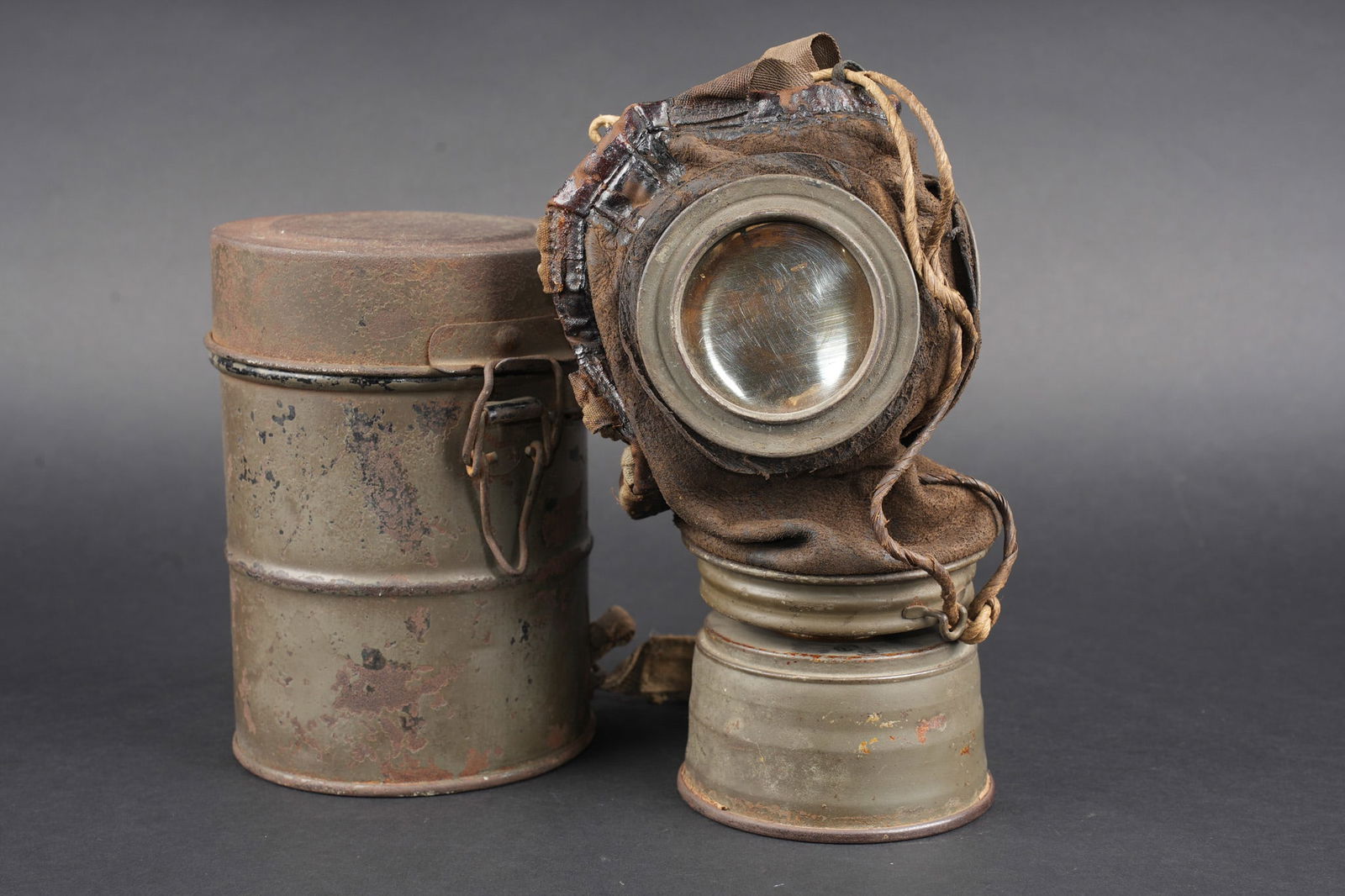 Masque anti-gaz allemand Lederschutzmaske. German anti-gas mask Lederschutzmaske.: Masque anti-gaz allemand Lederschutzmaske. Masque en cuir, souple, oculaires renforces, complet de ses sangles et de sa cordelette. Cartouche filtrante feldgrau, datee Feb. 18, en bon etat et facileme