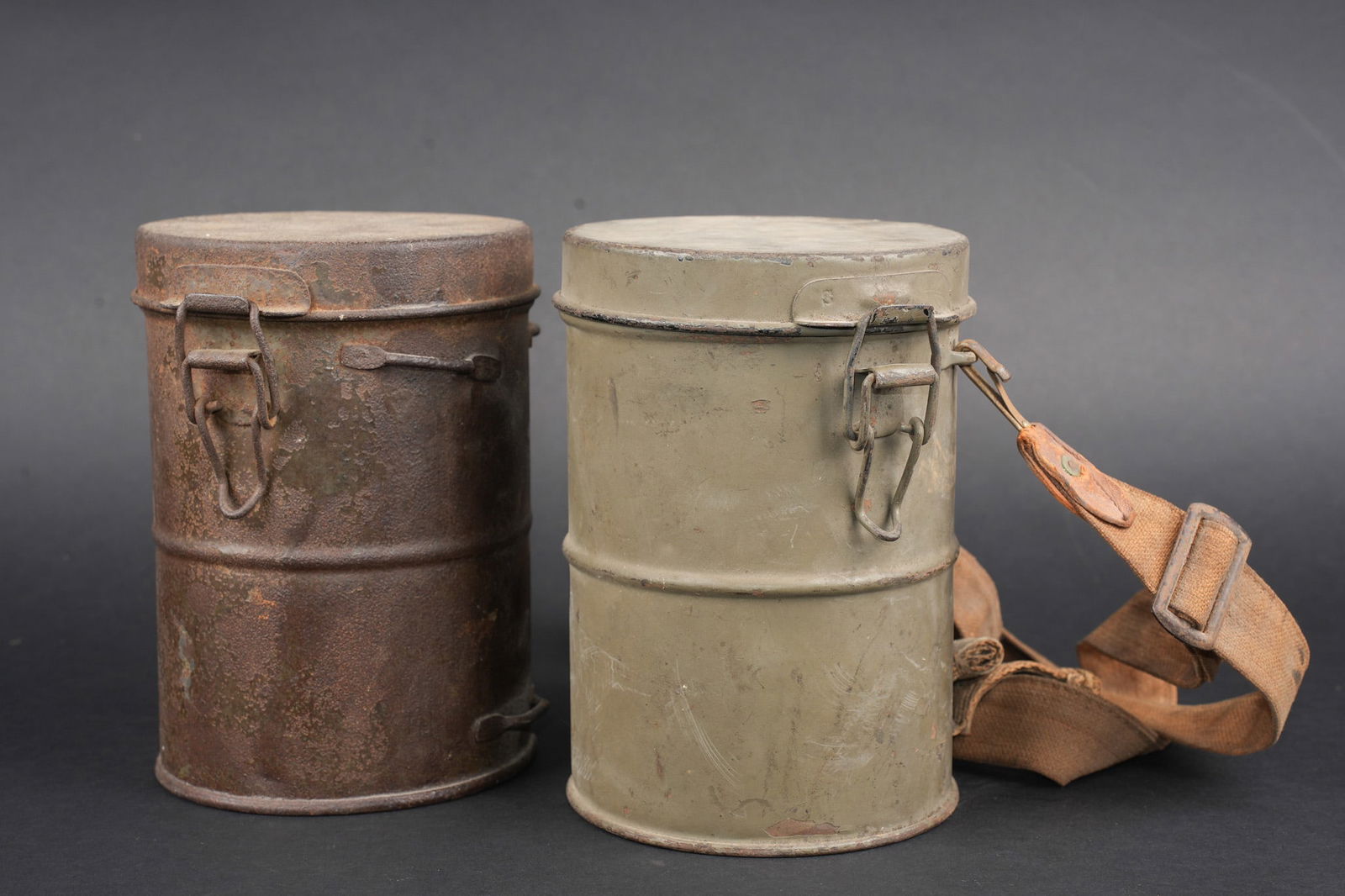 Lot de 2 boitiers de masques anti-gaz allemands Lederschutzmaske. Lot of two German Lederschutzmaske: Lot de 2 boitiers de masques anti-gaz allemands Lederschutzmaske. Un beau boitier avec la quasi-totalite de sa peinture feldgrau, vide, y compris le logement sous le couvercle. Avec une bretelle de sa
