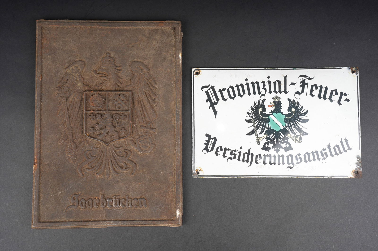 Plaque en fonte Saarbrucken et plaque emaillee d assurance incendie du Rheinland. Cast-iron plaque: Plaque en fonte Saarbrucken et plaque emaillee d assurance incendie du Rheinland. Jolie plaque emaillee a l aigle imperial et armes du Rheinland, marquee Provinzial Feuer-Versicherungsanstalt. Dimensi