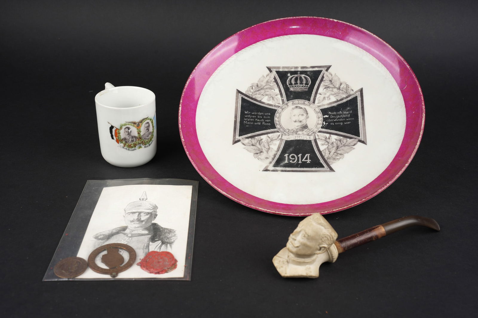 Lot d objets patriotique a l effigie du Kaiser, Kronprinz et von Mackensen. Lot of patriotic items: Lot d objets patriotique a l effigie du Kaiser, Kronprinz et von Mackensen. Une assiette en porcelaine a motif de croix de fer avec en son centre le buste du Kaiser, usure des motifs importante, diame