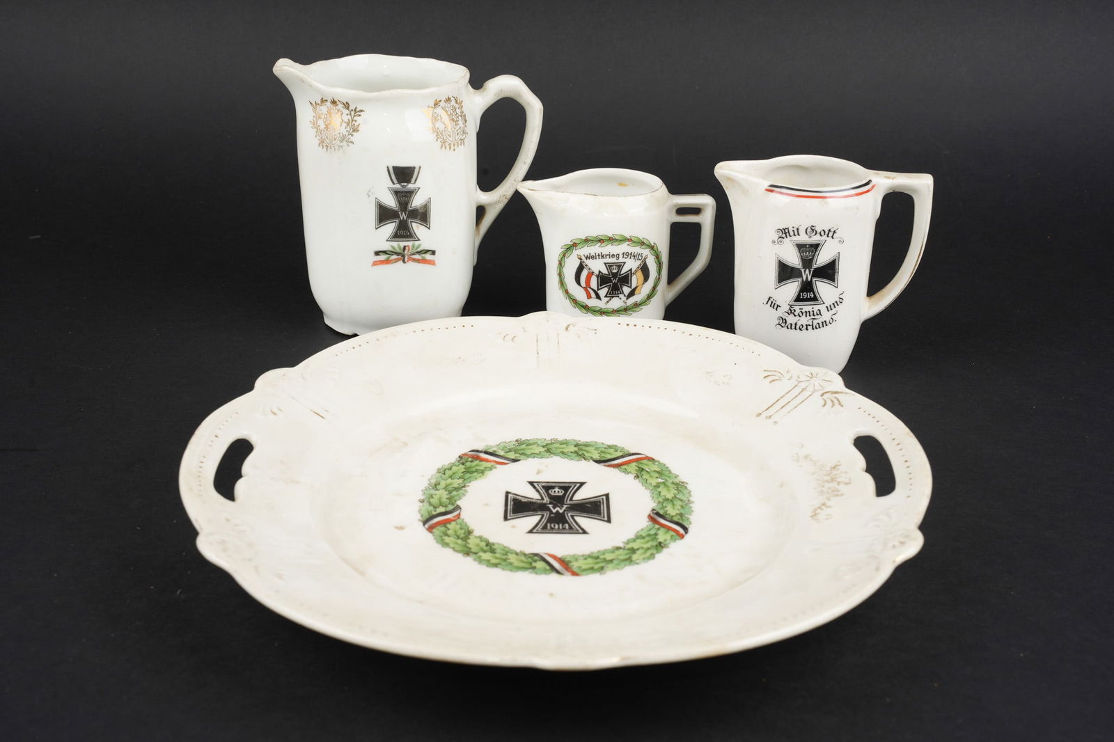 Lot de porcelaines patriotiques a motifs de Croix de Fer. Lot of patriotic porcelain decorated with: Lot de porcelaines patriotiques a motifs de Croix de Fer. Un plat, diametre environ 26 cm, usure importante. 3 pots a lait dont un de grande taille 12,5 cm. Usure d usage, patine. Patriotic porcelain