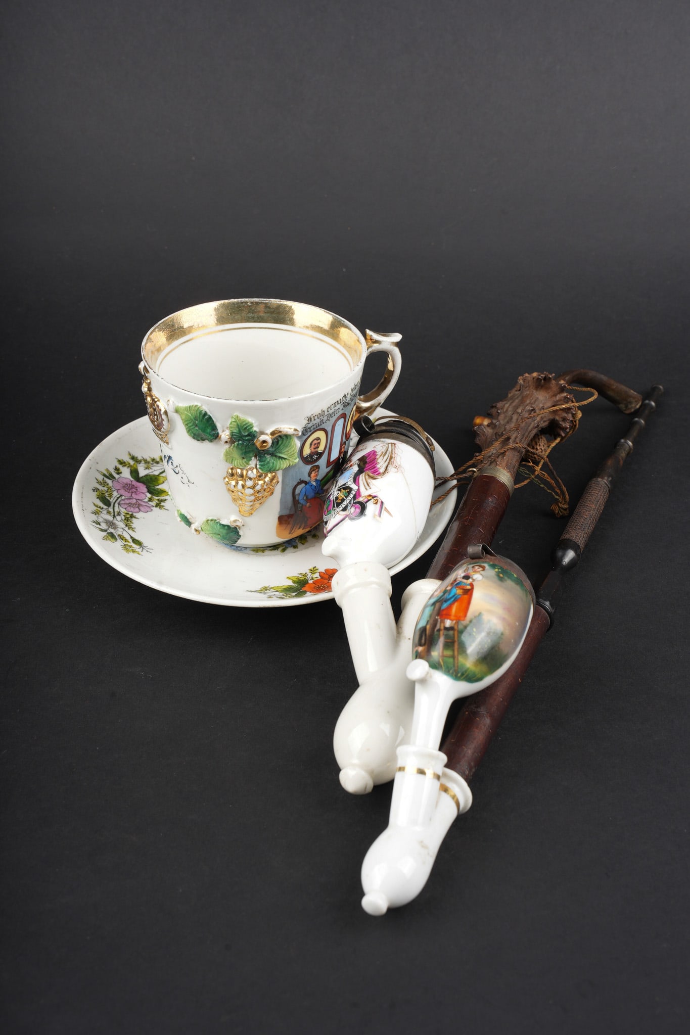 Ensemble de porcelaines de reservistes et civiles. Set of reservist and civilian porcelain pieces.: Ensemble de porcelaines de reservistes et civiles. Comprenant une tasse serigraphiee et rehaussee a la main, marquee, sauf erreur de lecture, Metz avec des motifs d artilleurs. Une sous tasse a motifs
