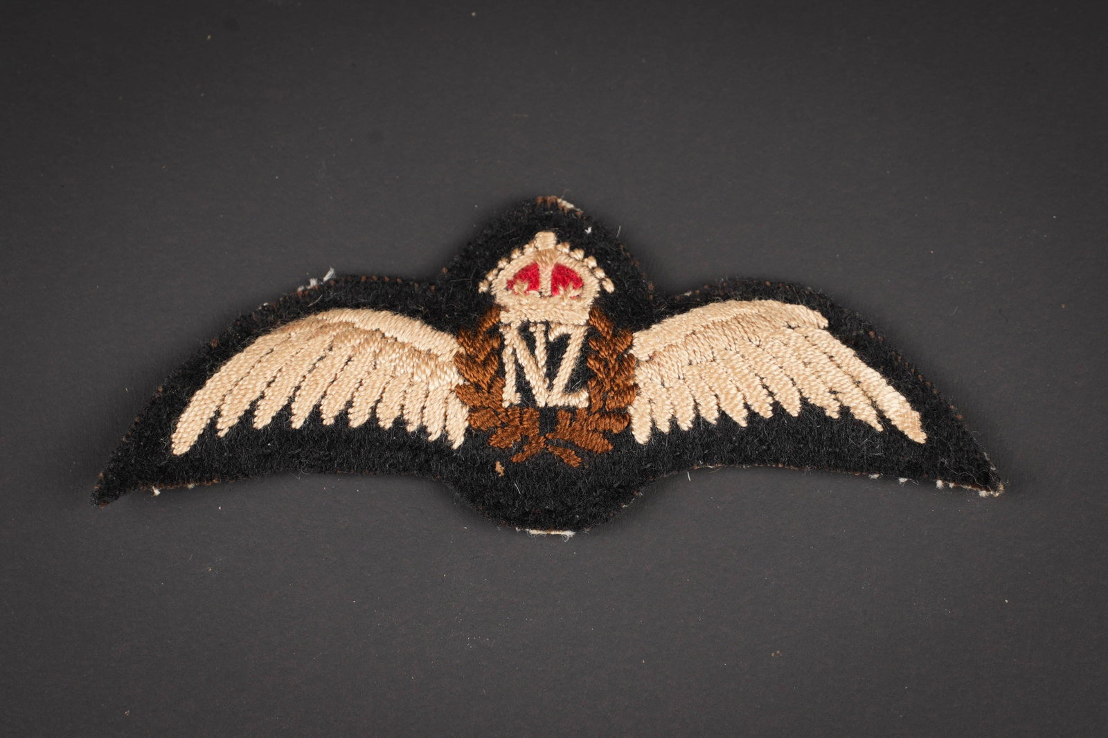 Brevet de pilote Neo Zelandais. New Zealand pilot’s brevet.: Brevet de pilote Neo Zelandais. Tres belle fabrication bombee. Dos de la piece recouvert d un tissu coton blanc. A noter une legere usure et patine de la piece. Etat I-. New Zealand pilot’s brevet. 