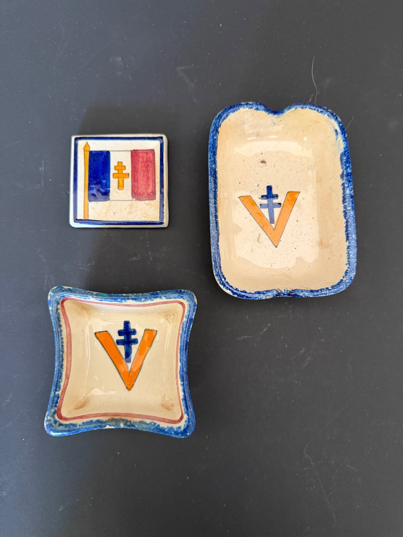 Cendriers liberations. Liberation ashtrays.: Cendriers liberation. Comprenant un cendrier en ceramique peinte, disposant d une croix de Lorraine et de la lettre V. Fabrication Henriot Quimper 78. Dimensions 6,7 x 9,2 cm. Un carreau de faience pe