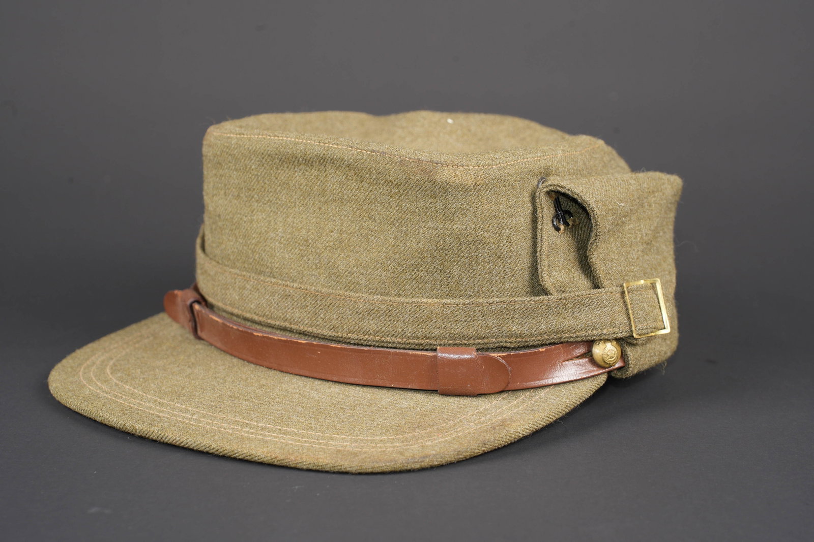Casquette d auxiliaire feminin canadien. Canadian women’s auxiliary cap.: Casquette d auxiliaire feminin canadien. En gabardine kaki. Insigne absent. Fausse jugulaire en cuir marron. Interieur double en satinette kaki. Reste de marquage canadien visible au fond de la coiffu