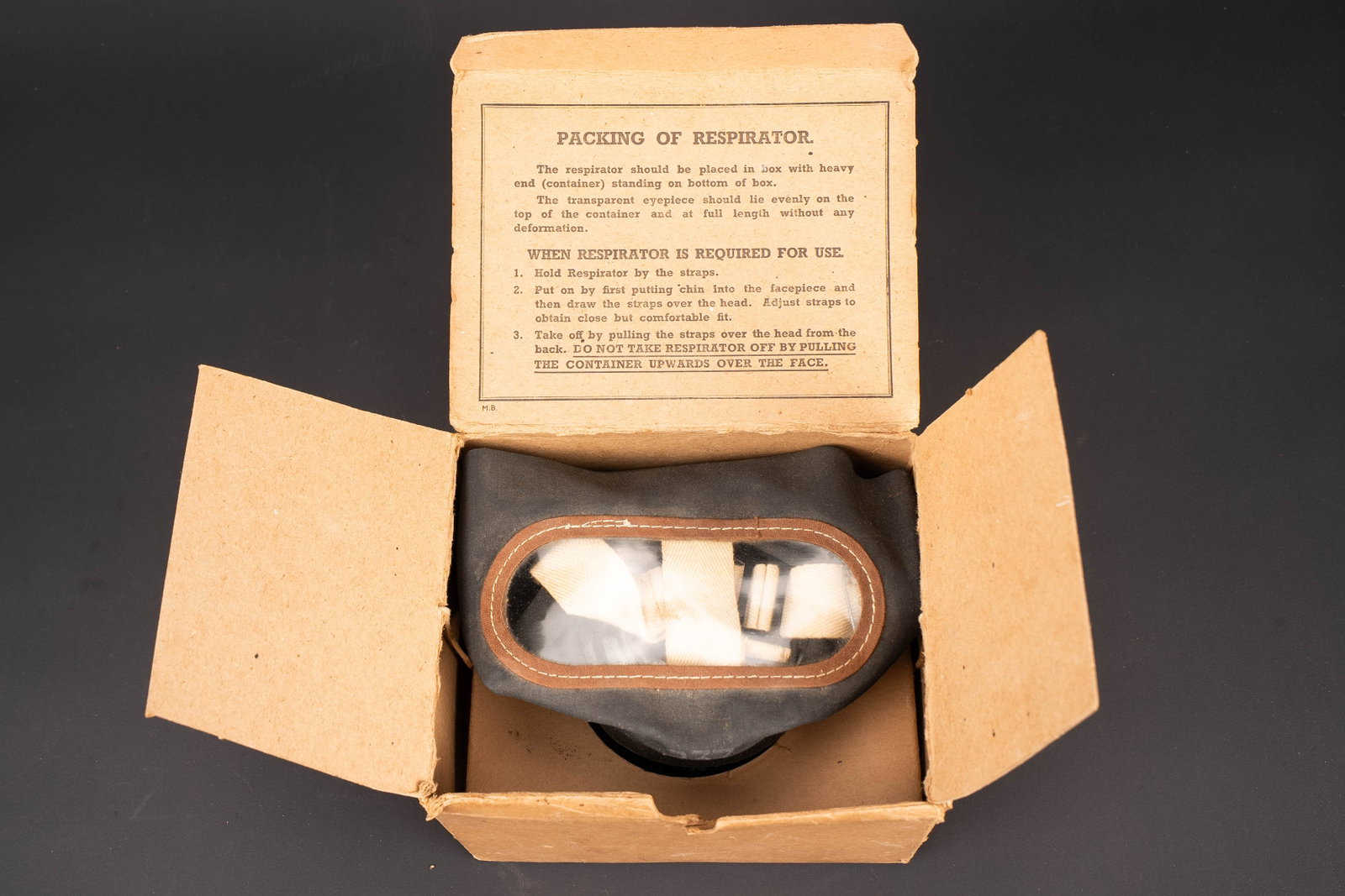 Masque anti-gaz civil britannique. British civilian gas mask.: Masque anti-gaz civil britannique. En caoutchouc noir, toute les sangles sont presentes. Filtre complet. Taille large. Dans sa boite en carton d origine. Notice d utilisation presente sous le rabat.