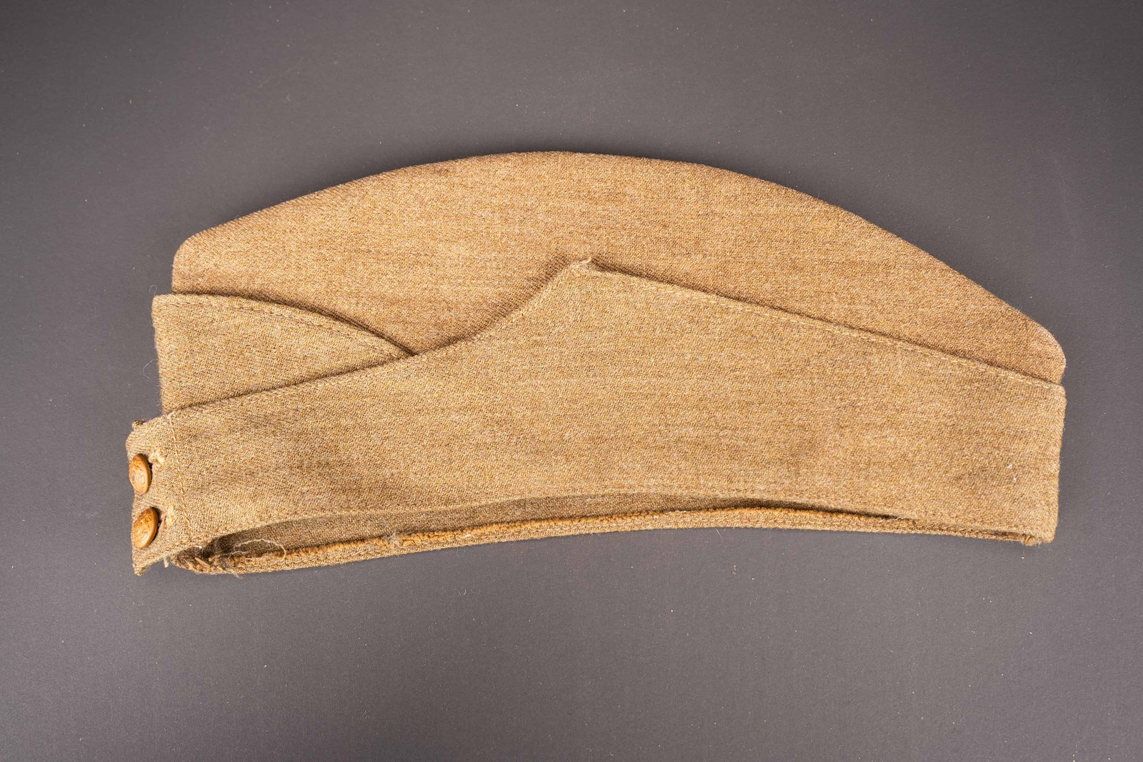 Calot britannique. British garrison cap.: Calot britannique. En tissu kaki. Deux boutons metalliques fermant les rabat. Une tache sur le cote. Interieur double en tissu coton beige. Bandeau de sudation en drap kaki. Date 1940. Taille 6 3/4.
