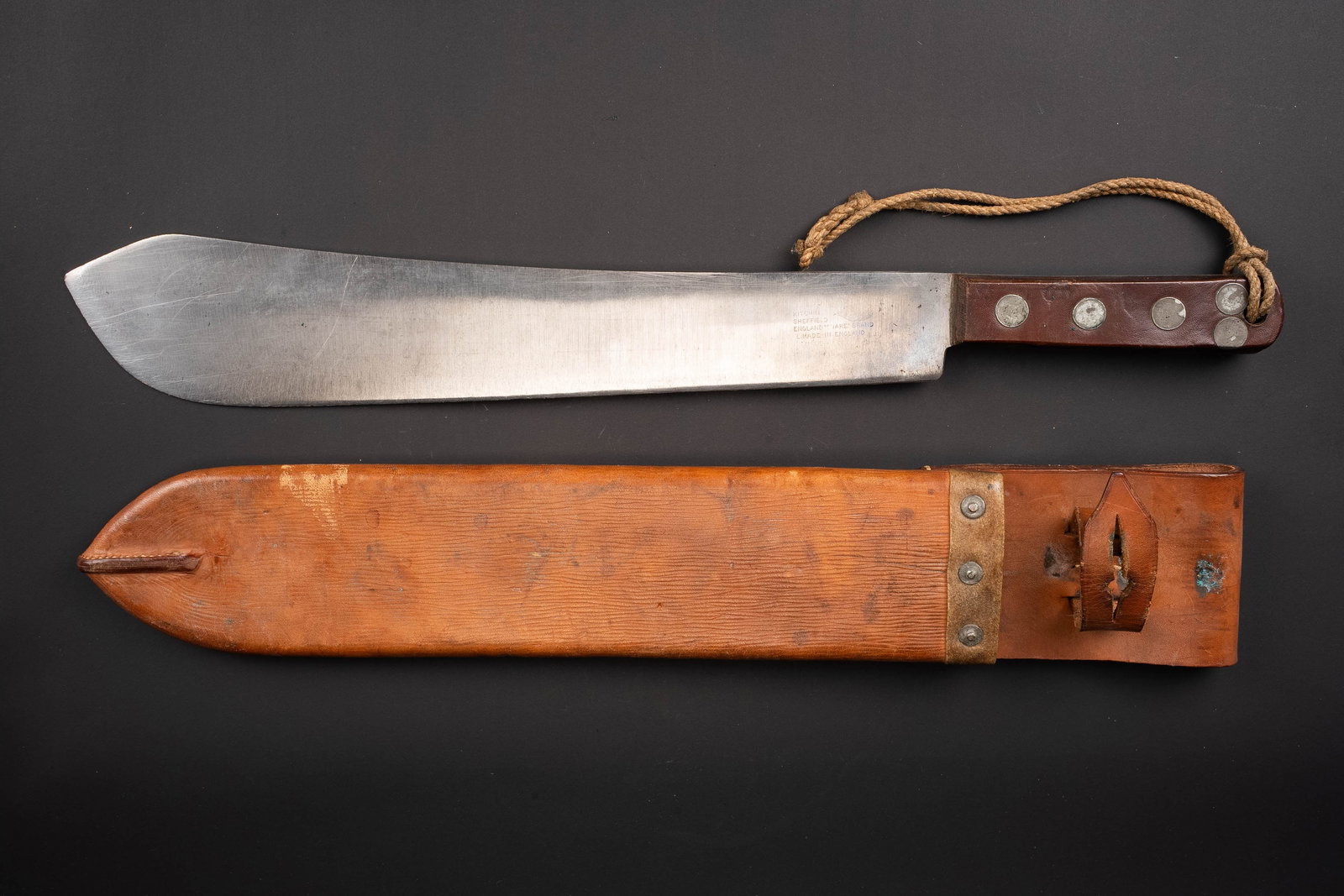 Machette britannique. British machete.: Machette britannique. Belle lame en metal. Poignee en bakelite marron, maintenue par cinq rivets. Marquages Sheffield avec broad arrow. Housse en epais cuir marron. La sangle de fermeture est complete