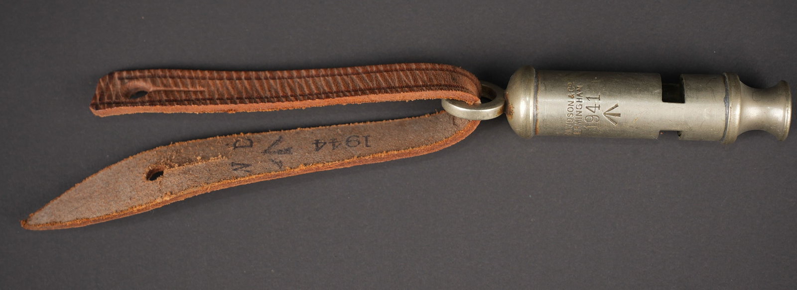 Sifflet britannique. British whistles: Sifflet britannique. En metal. Fonctionnel. Fabrication J Hudson & Co Birmingham 1941 avec broad arrow. Rare laniere en cuir marron, permettant d accrocher le sifflet a la boutonniere. Date 1944 avec