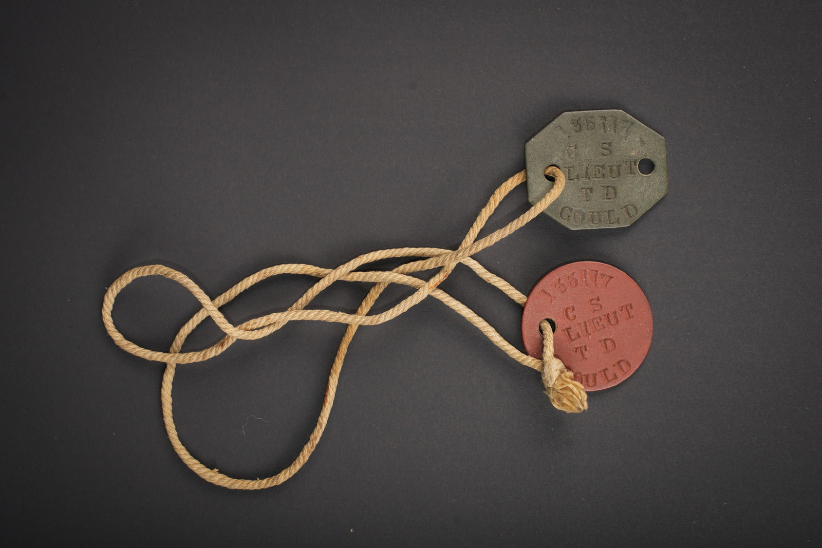 Plaques d identite britannique. British dog tags.: Plaques d identite britannique. Deux plaques en epais carton, couleur noir et rouge. Cordelette complete. Marquages 135117 CS Lieut TD Gould. A noter une legere usure et patine de la piece. Etat I-.