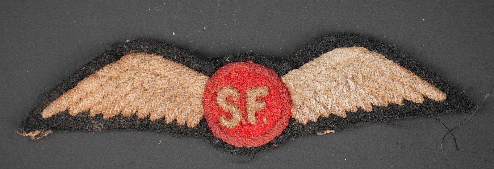 Insigne Jedburgh. Jedburgh insignia.: Insigne de poitrine Jedburgh. En tissu brode. Centre de la piece en feutrine rouge disposant des lettes SF brodee. Insigne decousu d un uniforme. A noter une certaine usure et patine de la piece.