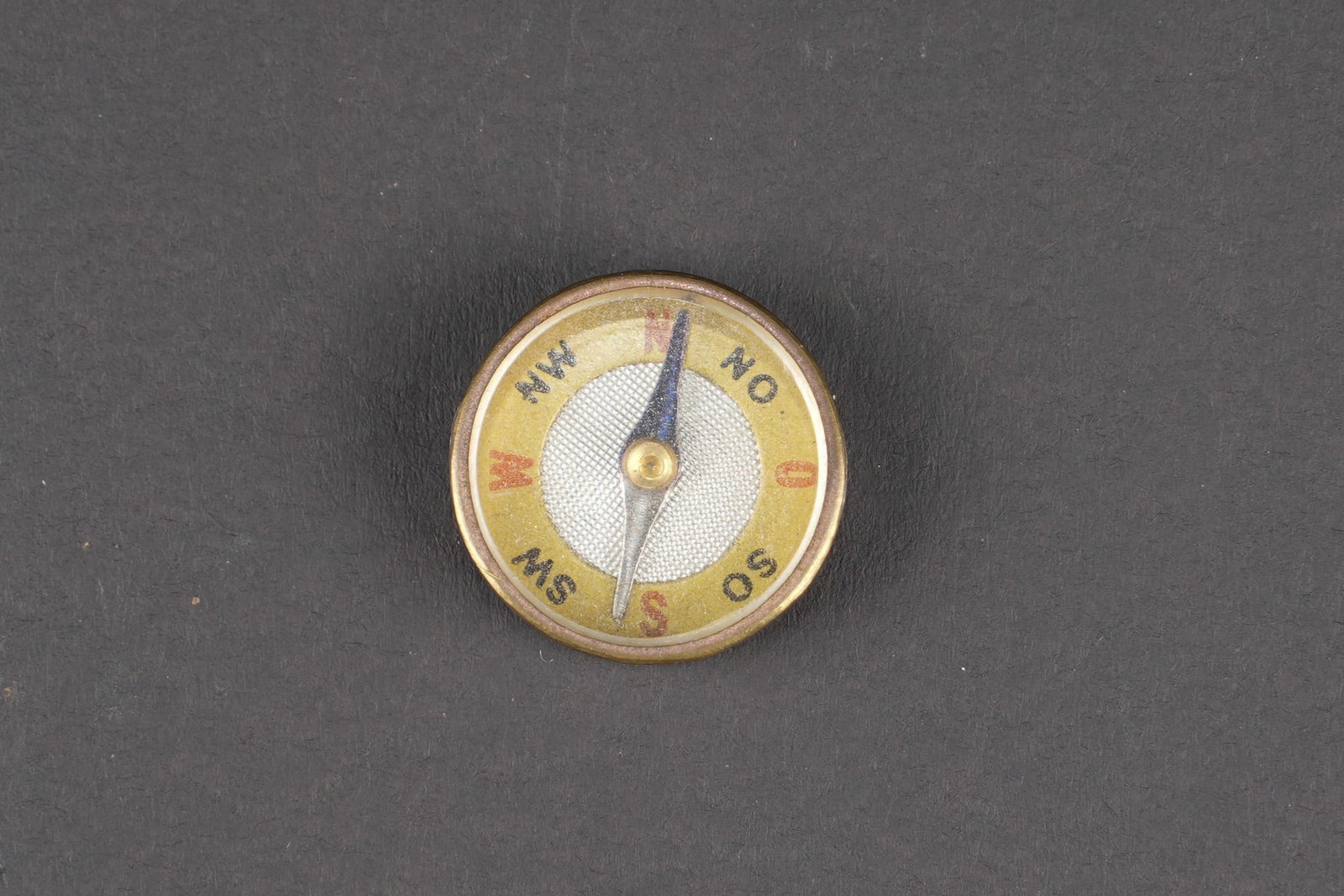 Boussole d evasion. Escape compass.: Boussole d evasion. En metal. Fonctionnelle. Diametre d environ 1 cm. Boussole souvent utilisee par les pilotes de la RAF. Ils dissimulaient les boussoles dans leurs bottes. A noter une certaine usure