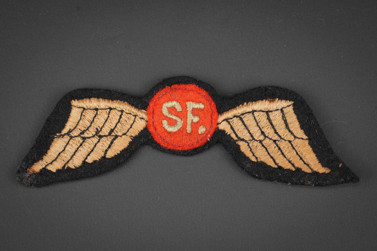 Insigne Jedburgh. Jedburgh insignia.: Insigne de poitrine Jedburgh. En tissu brode. Centre de la piece en feutrine rouge disposant des lettes SF brodee. Insigne decousu d un uniforme. A noter une certaine usure et patine de la piece.