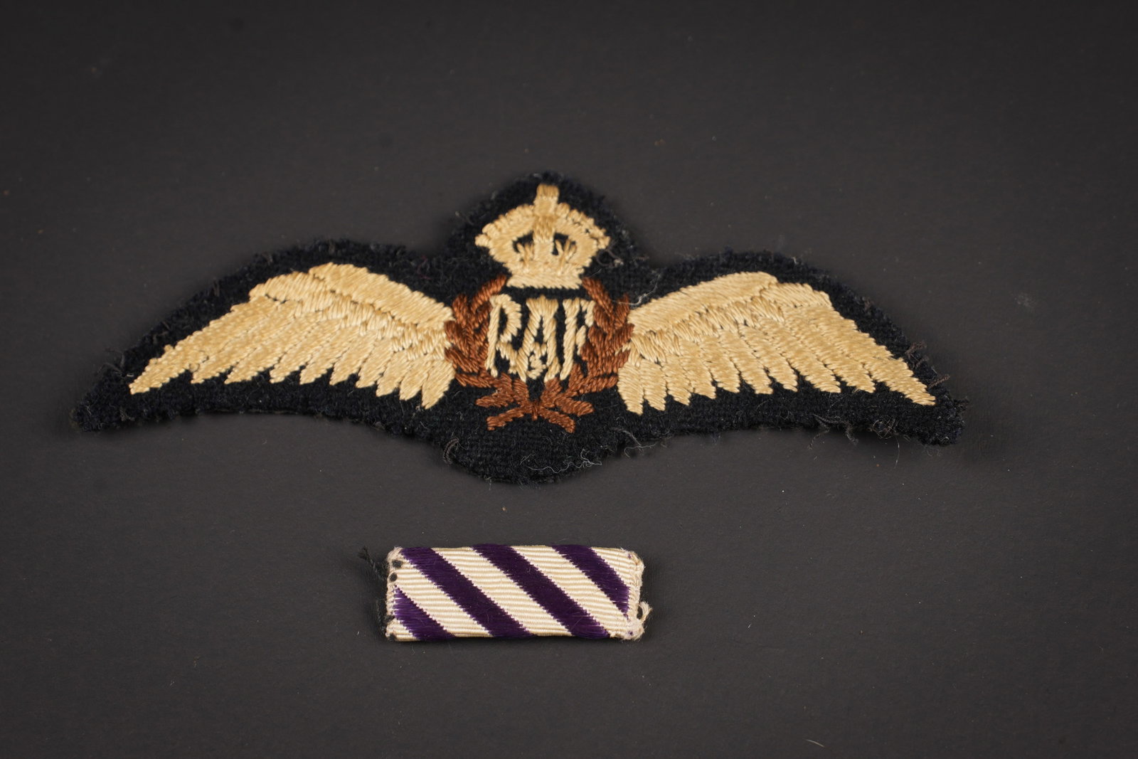 Brevet de pilote RAF. RAF pilot brevet.: Brevet de pilote RAF. Belel fabrication a plat. On y joint une barrette de ruban de decoration de la Distinguished Flying Cross. A noter une certaine usure et patine de la piece. Etat II+. RAF pilot