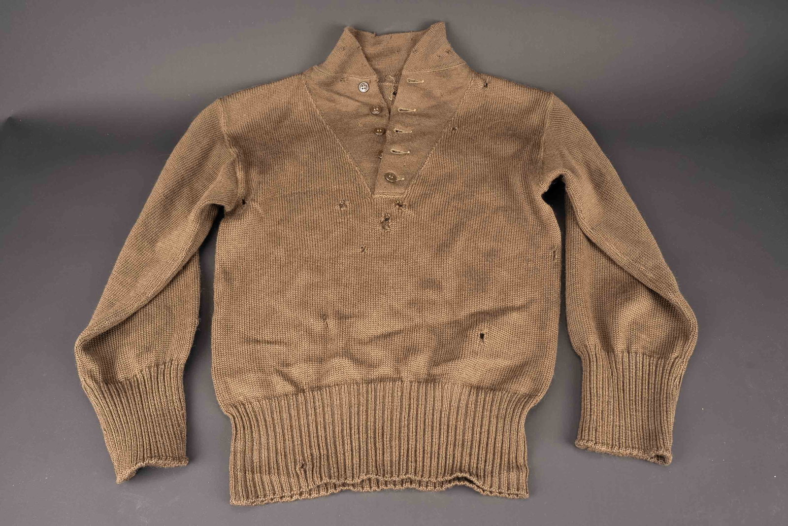 Pull 5 boutons US. US sweater.: Pull 5 boutons US. En laine marron. Tous les boutons sont presents. Etiquette absente. Nombreux trous de mite. A noter une certaine usure et patine de la piece, ainsi que de tres nombreux trous de