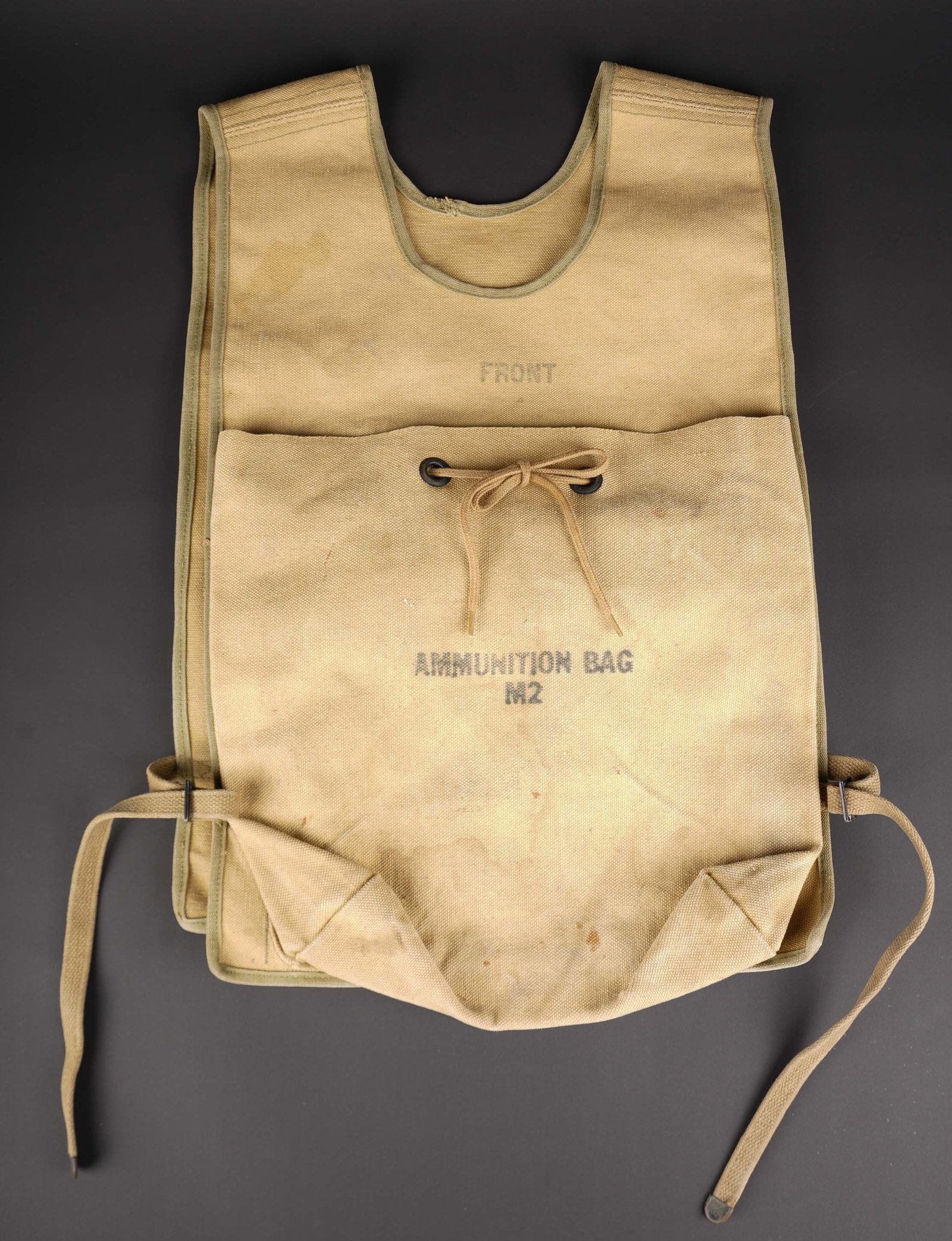 Chasuble Ammunition Bag M2. US M2 ammunition bag vest: Chasuble Ammunition Bag M2. En forte toile OD. Les cordons de serrage sont presents, ainsi que les sangles laterales. Marquages Ammunition Bag M2. A noter une certaine usure et patine de la piece.