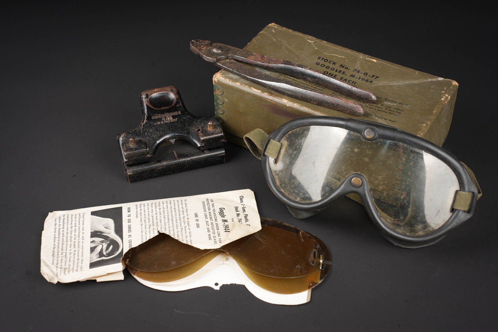 Equipements US. US Army equipment.: Equipements US. Comprenant une perforatrice de bureau, en metal, peinture noire a 70%, fonctionnelle, marquages Soennecken 232 DR Patent. Une pince en metal, bien marquee US. Une paire de lunette M-19