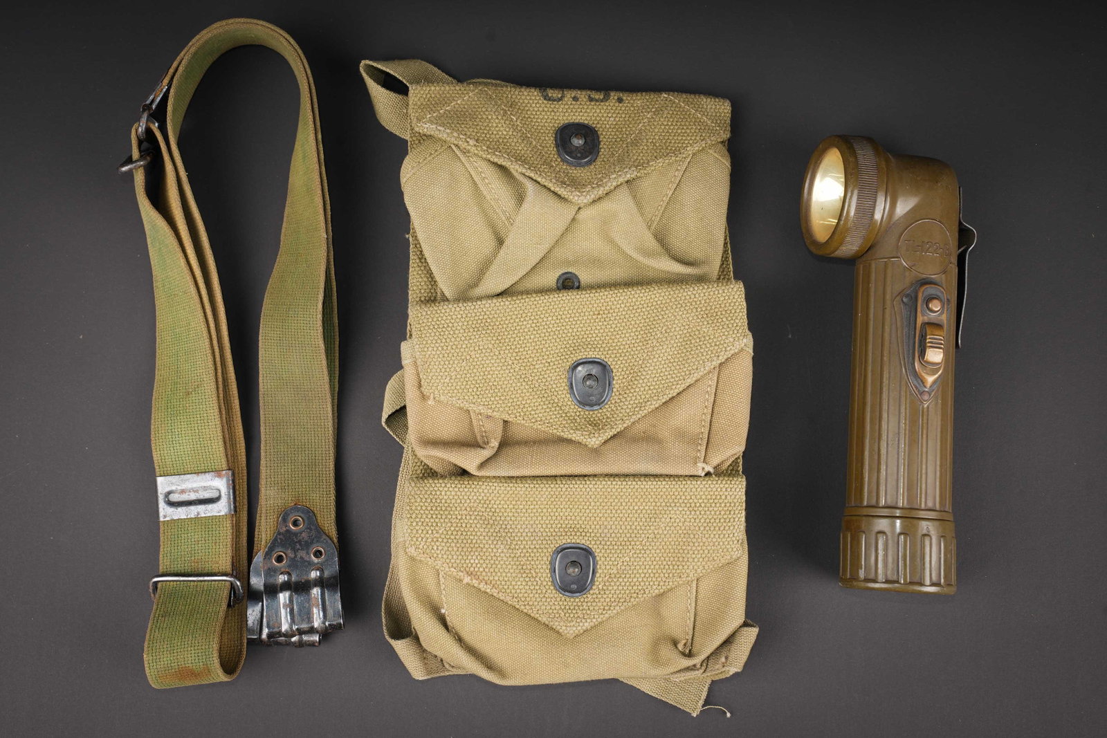 Equipements US. US Army equipment.: Equipements US. Comprenant une bretelle pour pistolet mitrailleur Thompson, en forte toile OD, toutes les pieces metalliques sont presentes. Sans marquages visibles. Une lampe de poche TL-122-B. En ba
