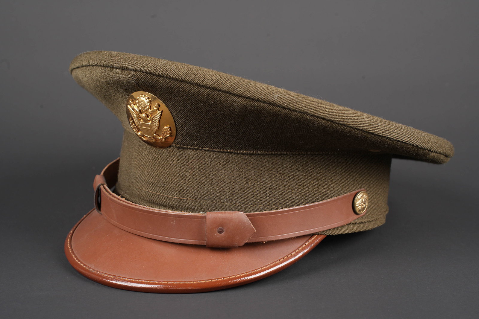 Casquette de sous-officier US. US ARMY NCO cap.: Casquette de sous-officier US. En gabardine chocolat. Insigne troupe en metal dore. Fausse jugulaire en cuir marron. Visiere en cuir. Linsigne na pas ete demonte afin de verifier les attaches.