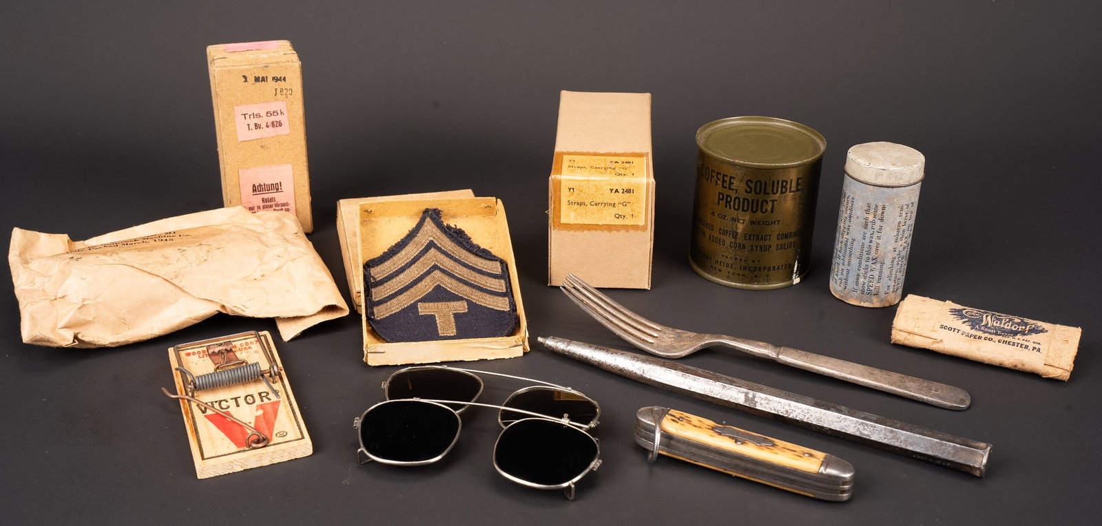Accessoires US. US Army accessories.: Accessoires US. Comprenant un relais radio en boite, date du mois de mai 1944. Une tapette a souris, marquee US Army. Un paquet de papiers toilette. Une boite en carton contenant un grade de manche.