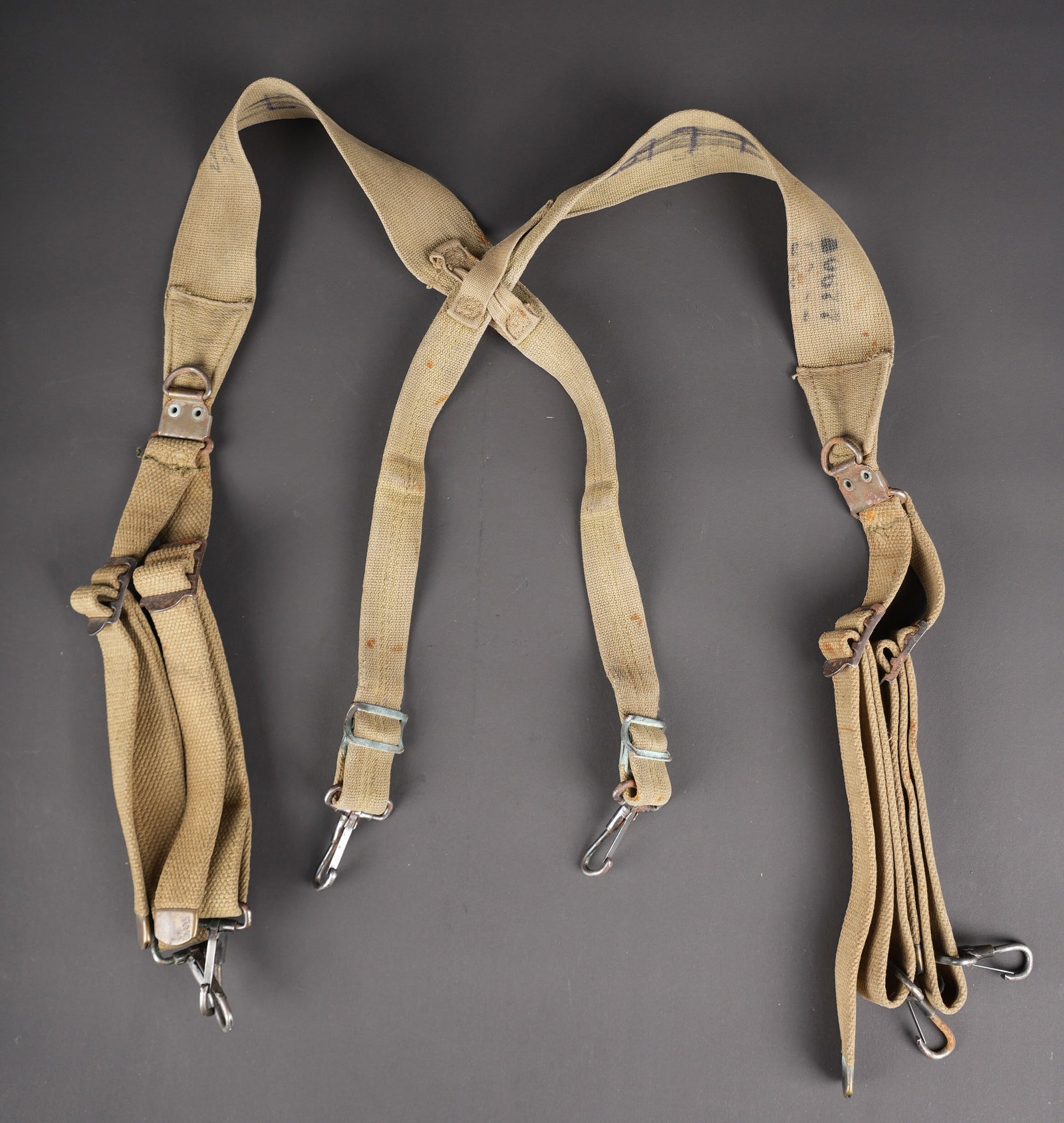 Brelage M-36 nominatif. US Army M-36 suspenders.: Brelage M-36 nominatif. En forte toile OD. Tous les mousquetons sont presents et fonctionnels. Nombreux laundry number partiellement illisibles. A noter une certaine usure et patine de la piece, ainsi