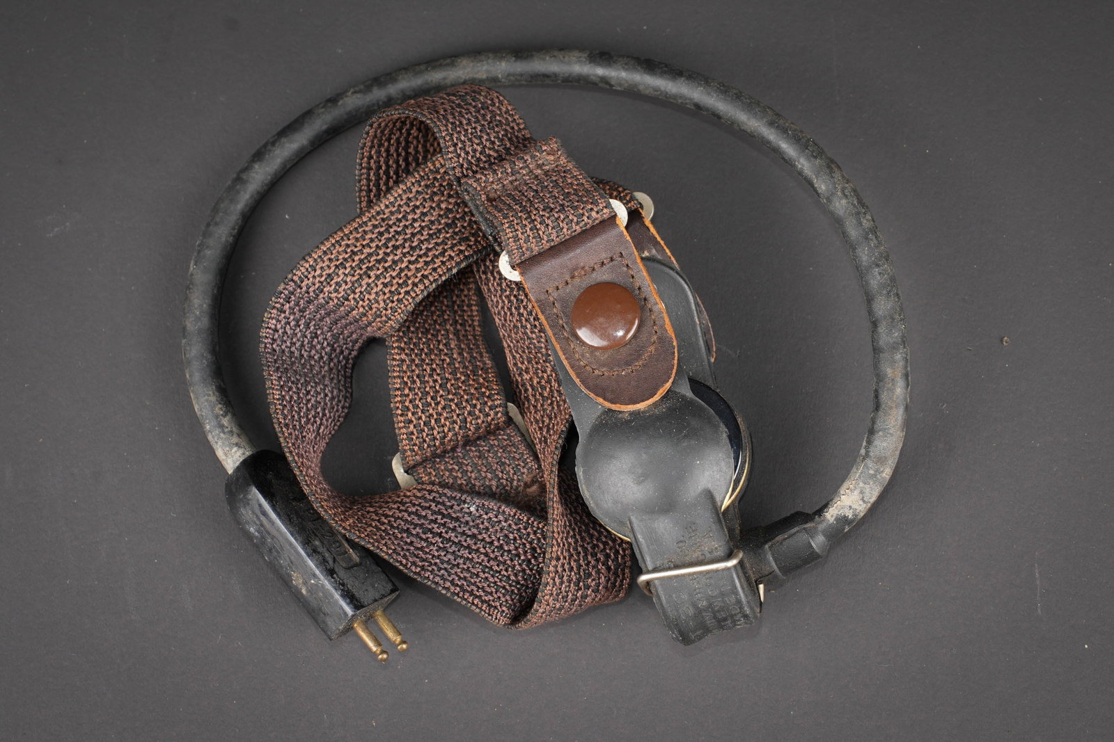 Laryngophone US. US throat microphone: Laryngophone US. Structure en caoutchouc noir. Fabrication T-30. Cable et prise present. Elastique souple. Les boutons pressions sont fonctionnels. A noter une certaine usure et patine de la piece. Et