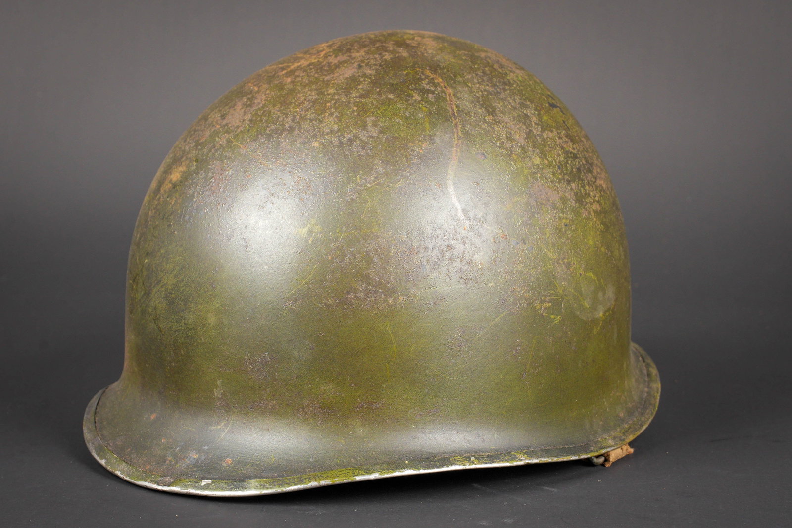 Casque USM1. US M1 Helmet: Casque USM1. Coque de casque USM1, fermeture du jonc a lavant. Numero de lot illisible. Pontets fixes. Seule la petite jugulaire est presente, mais elle est incomplete. Coque decapee et partiellement 