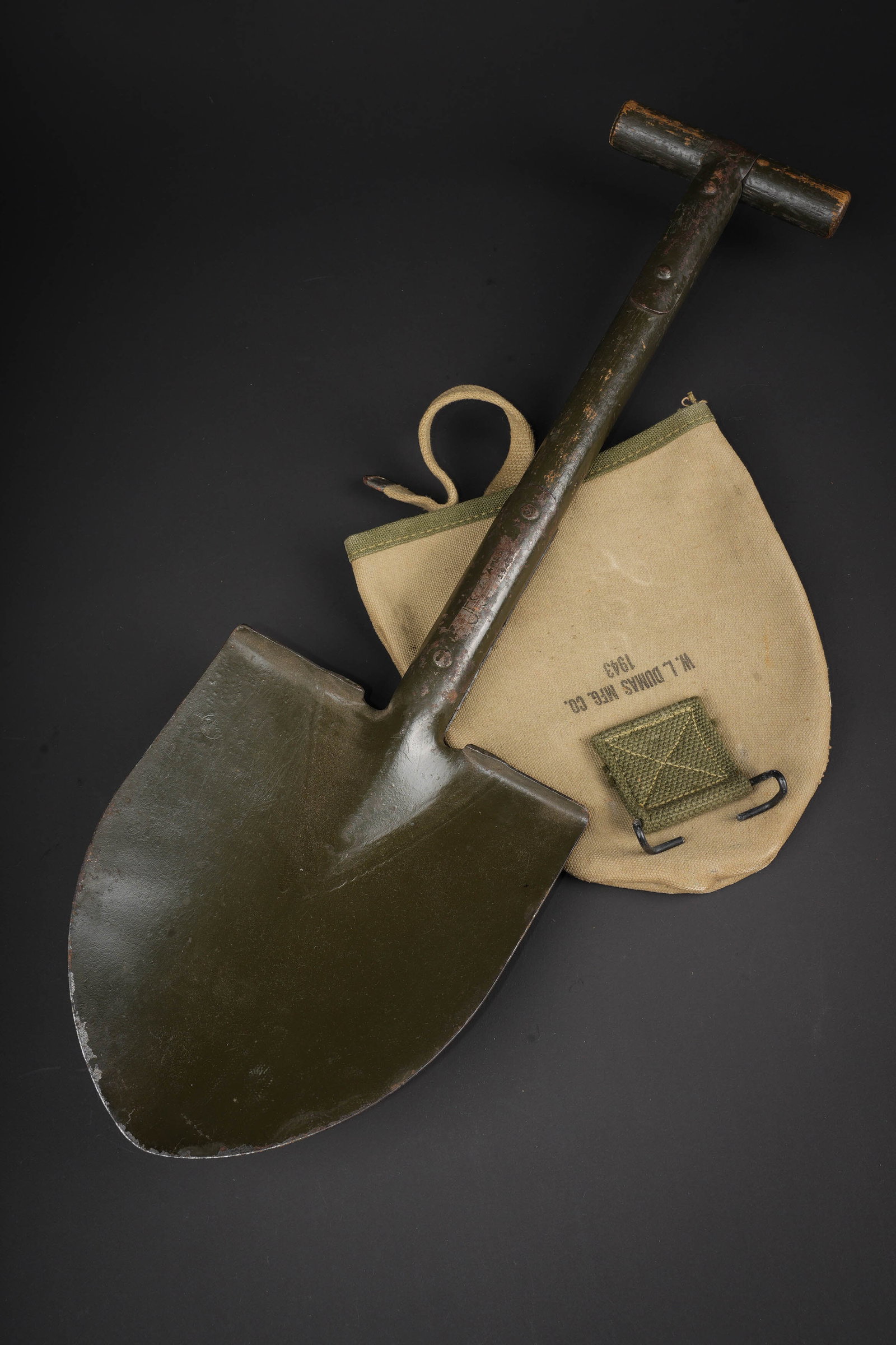 Pelle en T US. US T-handled shovel.: Pelle en T US. Partie en bois repeinte. Partie metallique bien marquee US AMES 1943. Housse en forte toile OD bicolore. Le crochet de fixation au ceinturon est present. Beau marquage US sur la face av