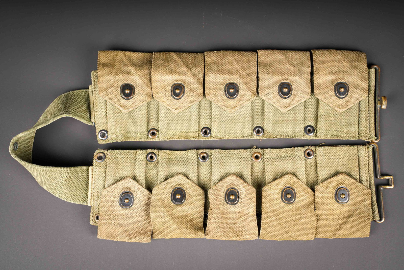Ceinturon garand. M1 Garand cartridge belt.: Ceinturon Garand. En forte toile OD7. Tous les boutons pressions sont fonctionnels. Bouclerie en laiton. Sans marquages visibles. A noter une certaine usure et patine de la piece, ainsi que des taches