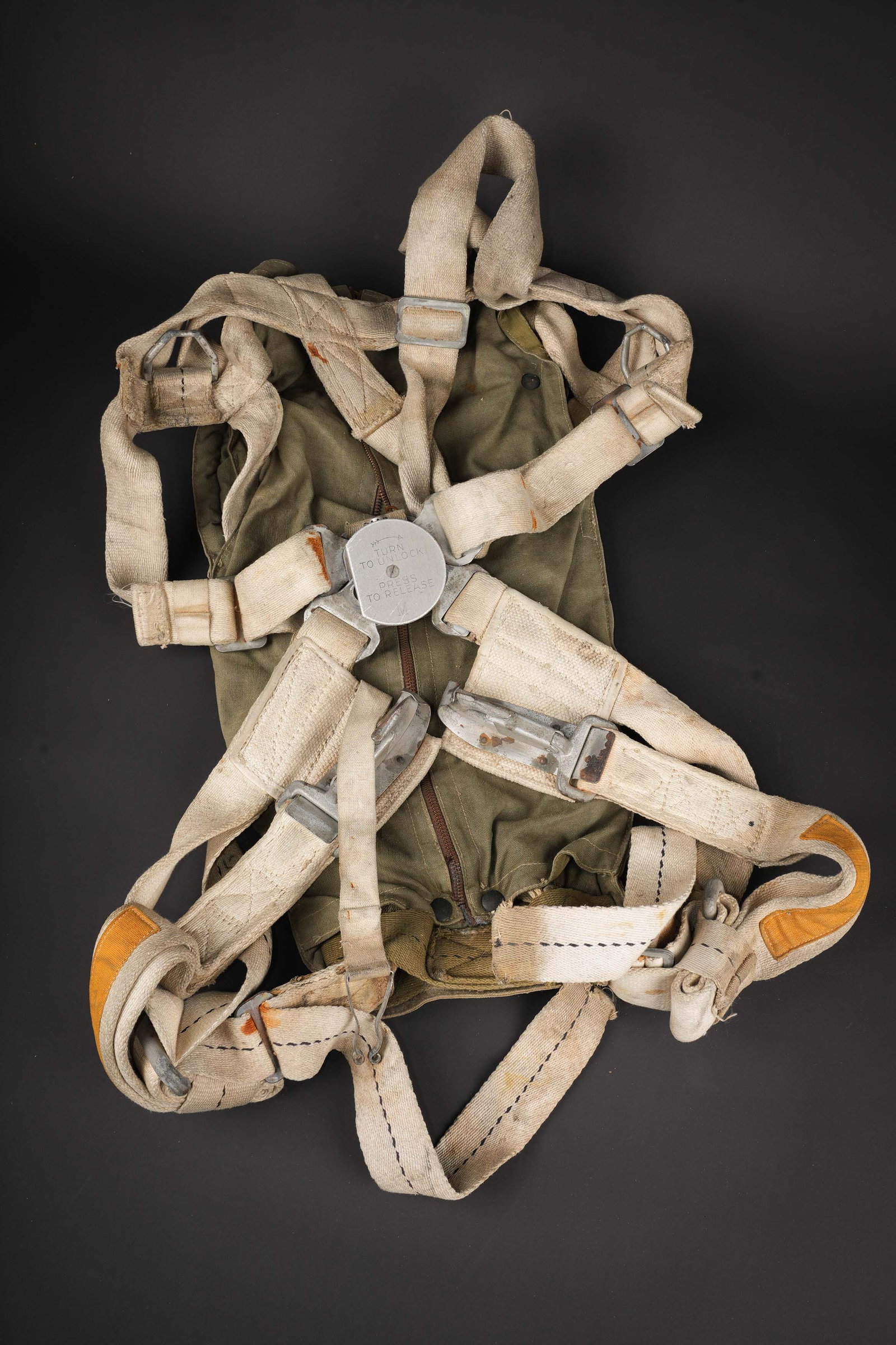 Harnais de parachute A-4. A-4 parachute harness.: Harnais de parachute A-4. En epaisse toile blanche surpiquee de fil blanc. Harnais complet avec tous ses crochets en metal. Boitier de degrafage rapide en metal, marque 44D9334-J Oneida. Le harnais di