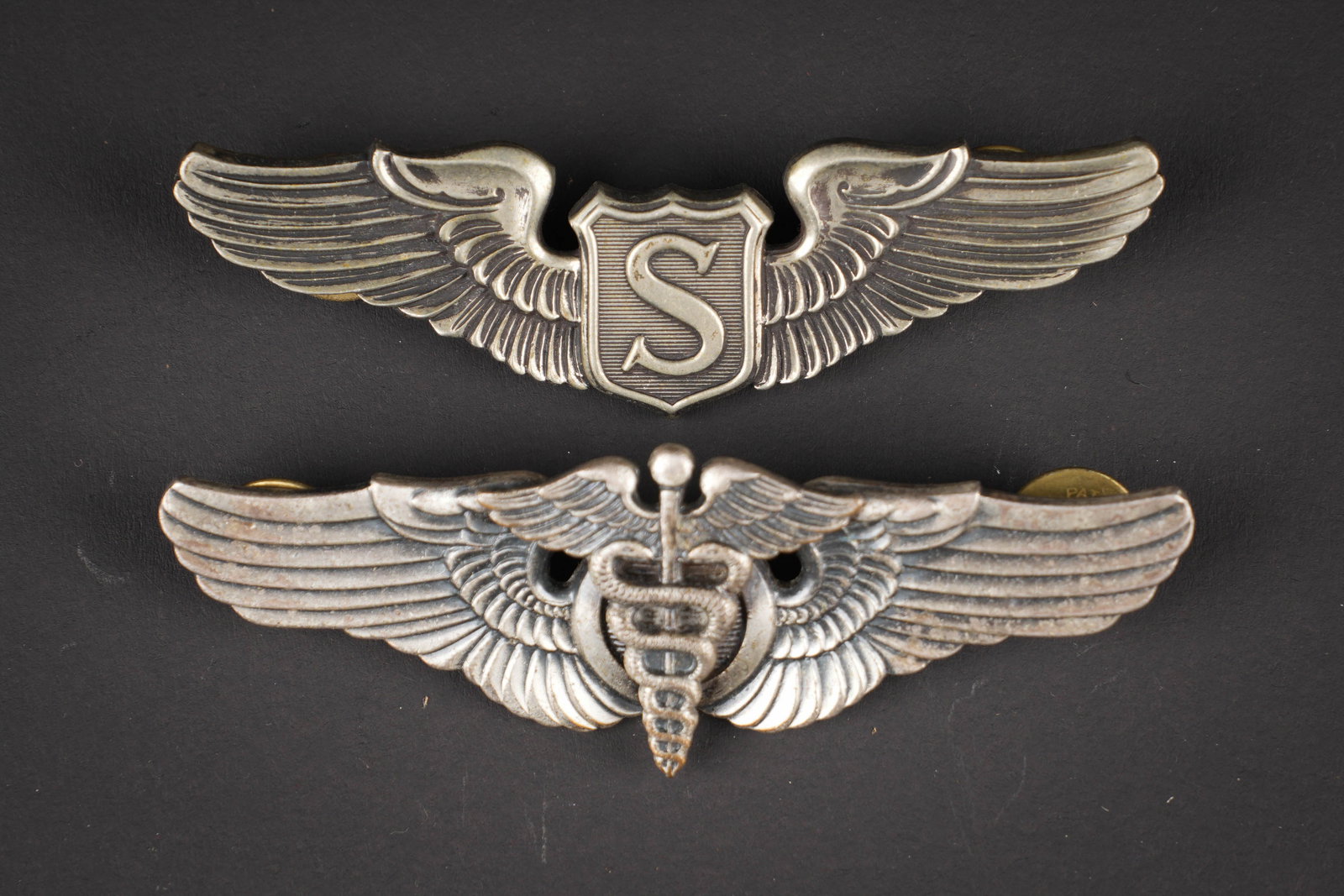 Brevet de pilote US. US pilot wings.: Brevets de pilote US. Comprenant un brevet de Service Pilot , couleur argent, logo du fabricant, attaches completes. Un brevet de Flight Surgeon, couleur argent, Vanguard NY. Attache complete. A