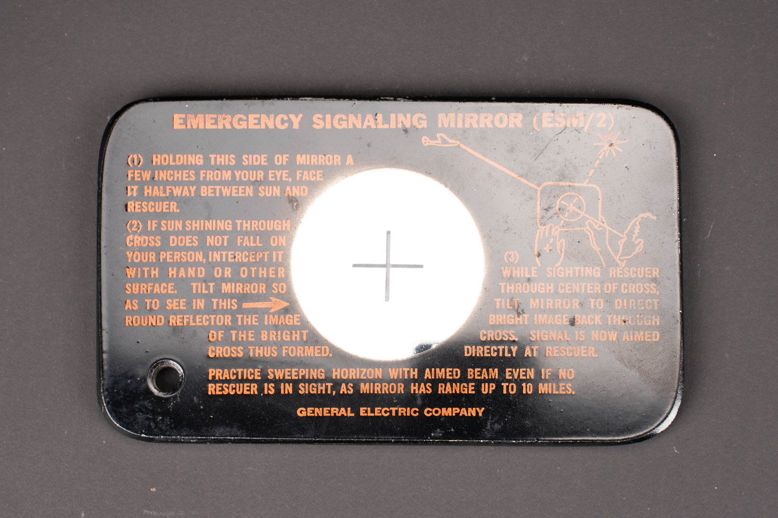 Miroir de survie USAAF. USAAF survival mirror.: Miroir de survie USAAF. En bakelite noir. Cordelette absente. Notice dutilisation au dos du miroir. Fabrication General Electric Company. A noter une certaine usure et patine de la piece. Etat II+. US