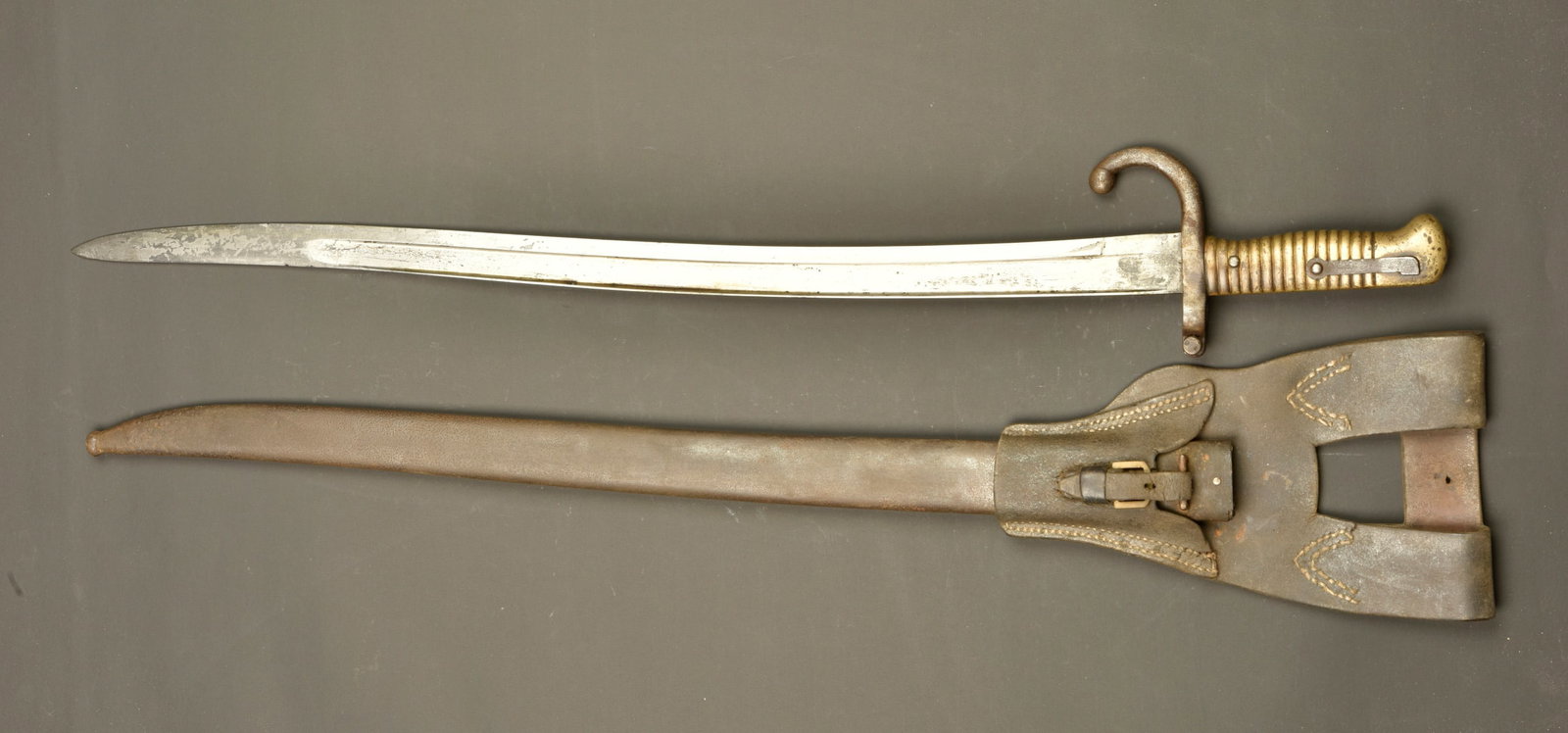 Sabre baionnette Chassepot modele 1866 avec porte fourreau. Chassepot Model 1866 sword bayonet with: Sabre baionnette Chassepot modele 1866 avec porte fourreau. Lame yatagan a dos plat, marquee de la manufacture de St Etienne Octobre 1869. Poignee laiton striee. Bouton ressort fonctionnel. Usure, cou