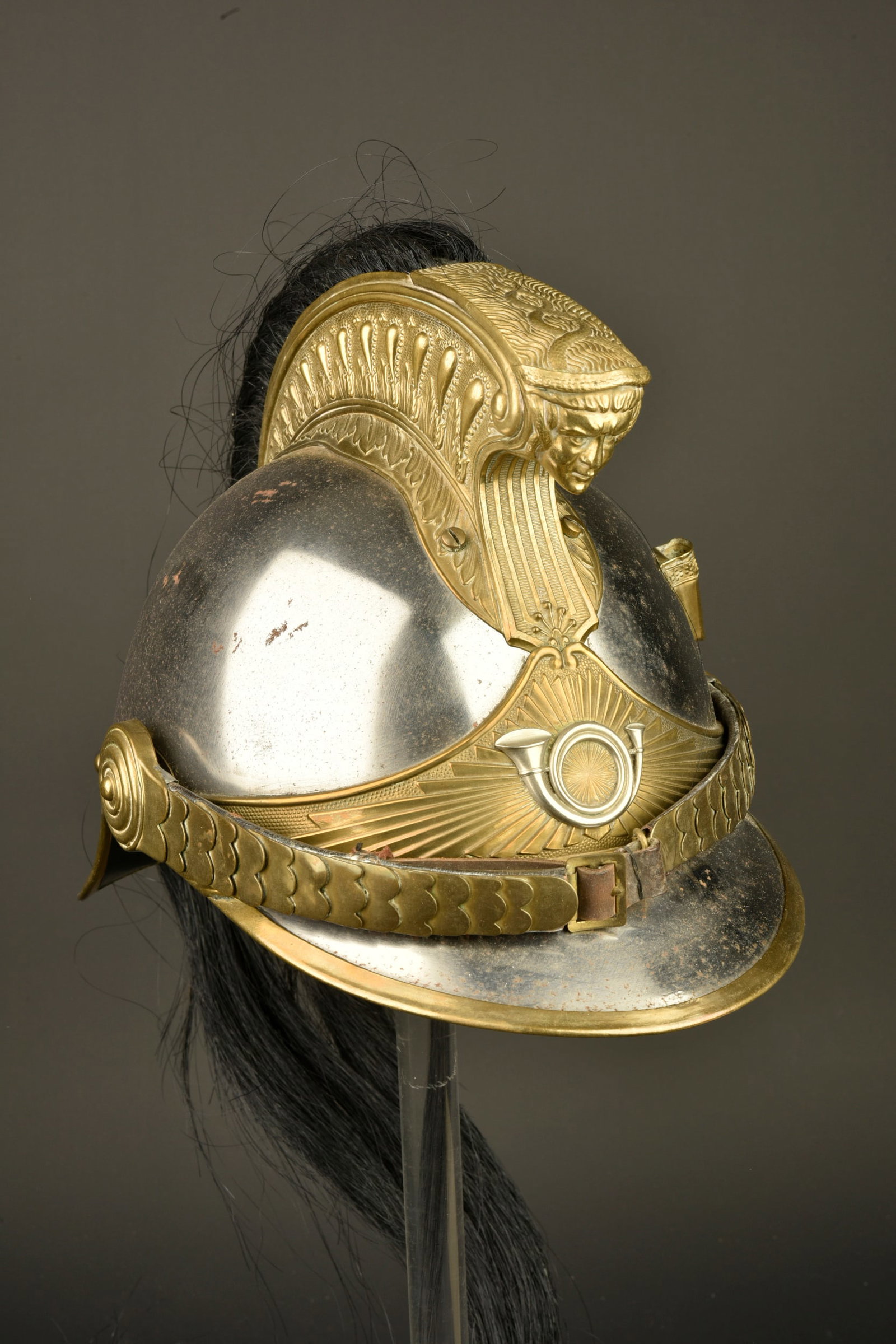 Casque a cimier et criniere de chasseur a cheval. Crested helmet with horsehair plume of a Chasseur: Casque a cimier et criniere de chasseur a cheval. Casque modele 1913 en acier nickele du fabricant Siraudin. Cimier a godrons, jugulaires a ecailles festonnees doublees de cuir, bandeau rayonnant a mo