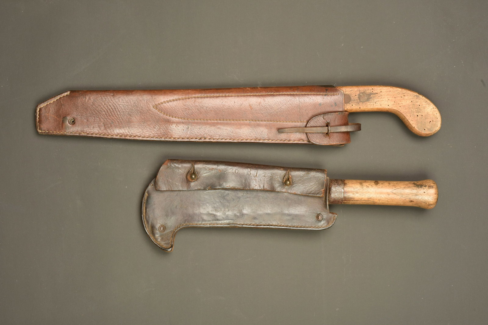 Scie et serpe francaises. French saw and billhook: Scie et serpe francaises. Scie egoine, pas de marquage visible, poignee legerement vermoulue. Dans un bel etui en cuir marron. Une serpe datee 1917, oxydation, dans son etui cuir fabricant la sellerie