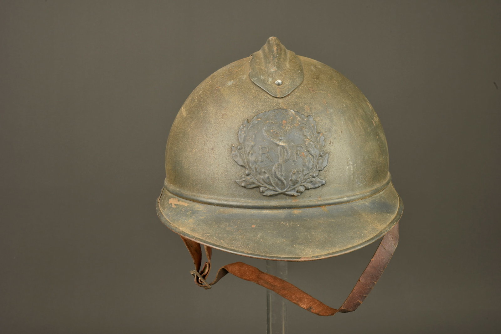 Casque Adrian du Service de Sante des Armees. Adrian helmet of the French Army Medical Service: Casque Adrian du Service de Sante des Armees. Casque bleu horizon, une couche de crasse lui donne un aspect gris vert. Attribut du SSA. Complet avec sa coiffe 1er type en cuir noir, gaufrettes, jugula