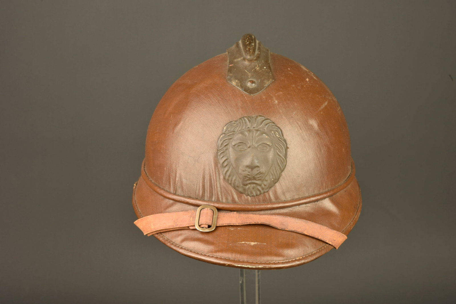 Casque belge en liege recouvert de toile moutarde. Belgian cork helmet covered in mustard canvas: Casque belge en liege recouvert de toile moutarde. Tres beau casque type Adrian en liege recouvert de toile enduite moutarde marron. Attribut au lion. Coiffe a dents de loup a bouts carres et œillets